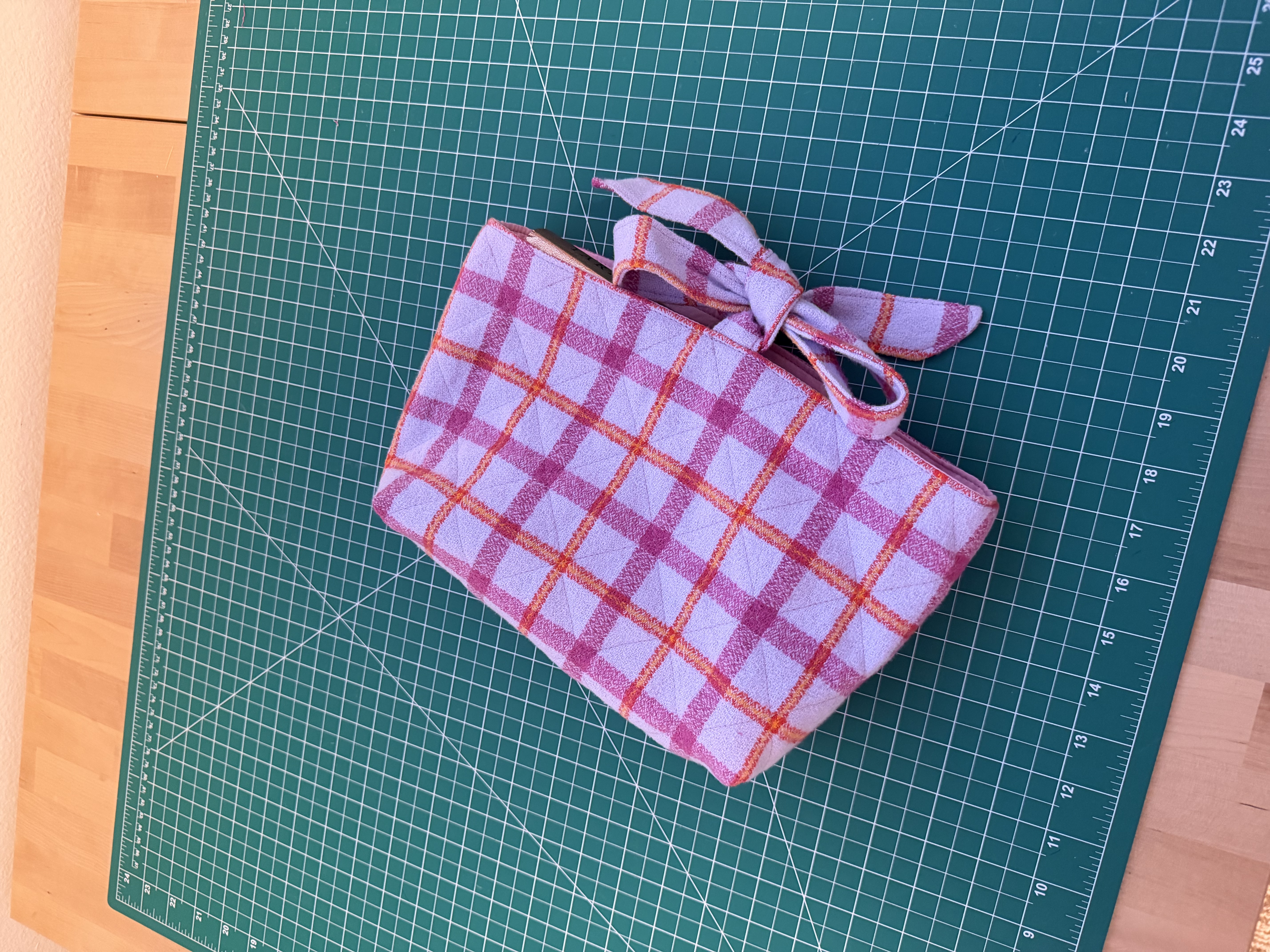 Finished quilted fabric book sleeve in a pink and orange plaid flannel with a tied bow closure